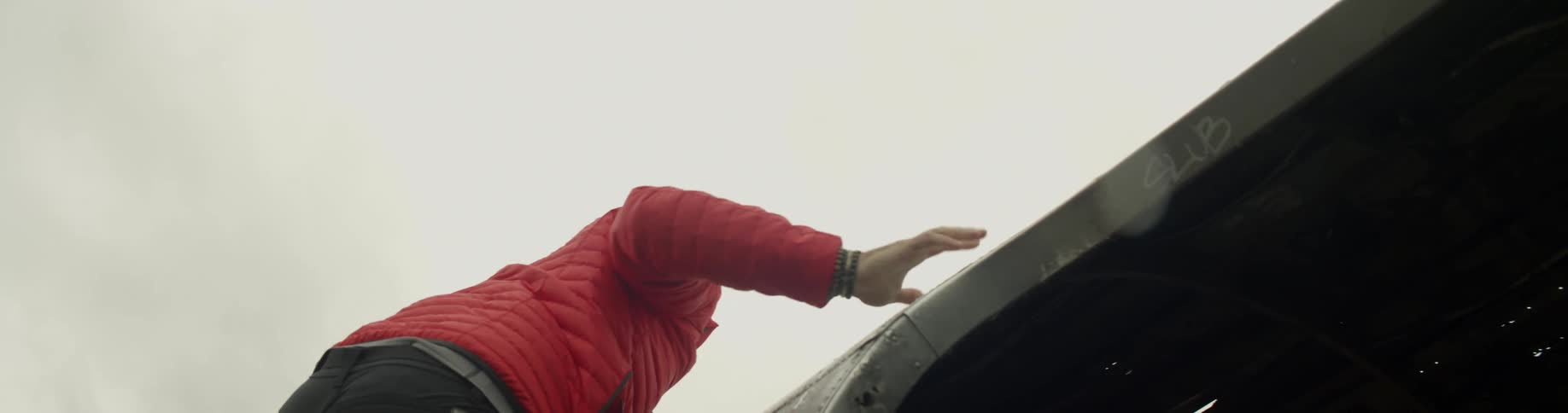 A person climbs the windows on an abandoned airplane to get to the top of it
