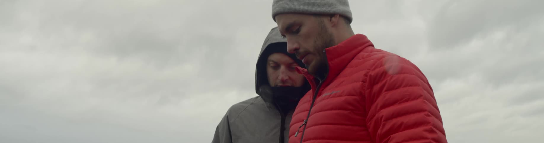A pair of men examining the screen on a camera outdoors during the day