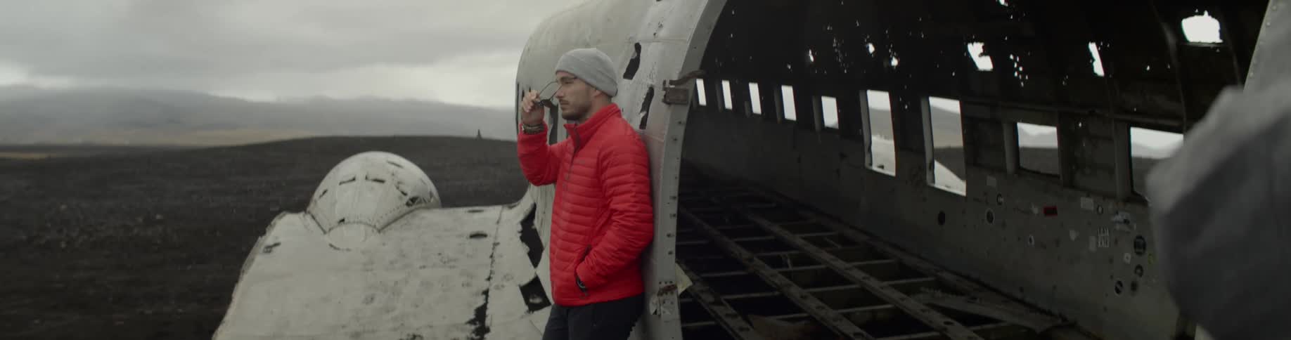 Man standing against an abandoned airplane in a field