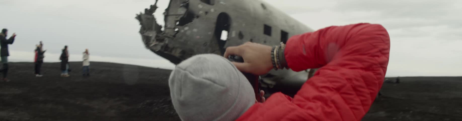 A man photographs another man that is standing atop a destroyed airplane