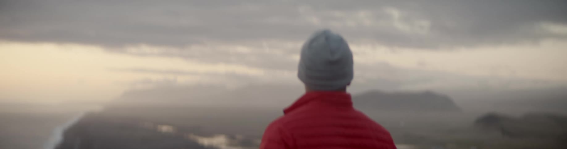 A man stands and looks across the hills and towards a lake