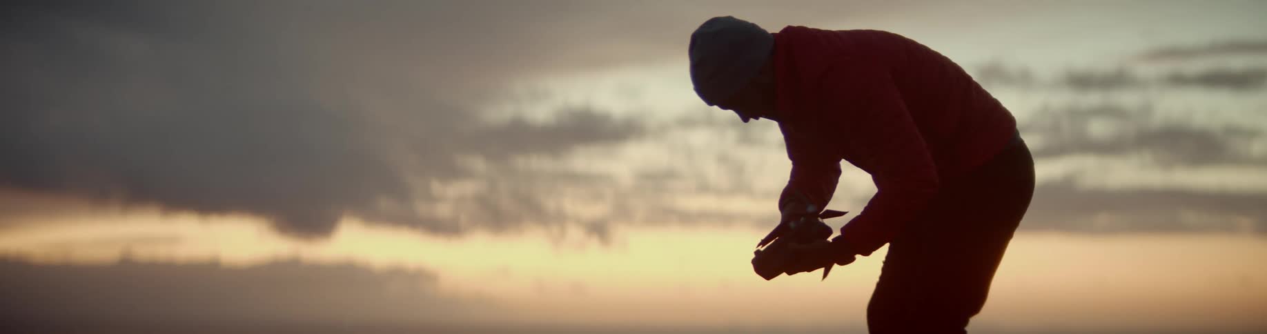 Man holds a drone as he stands under a cloudy sky