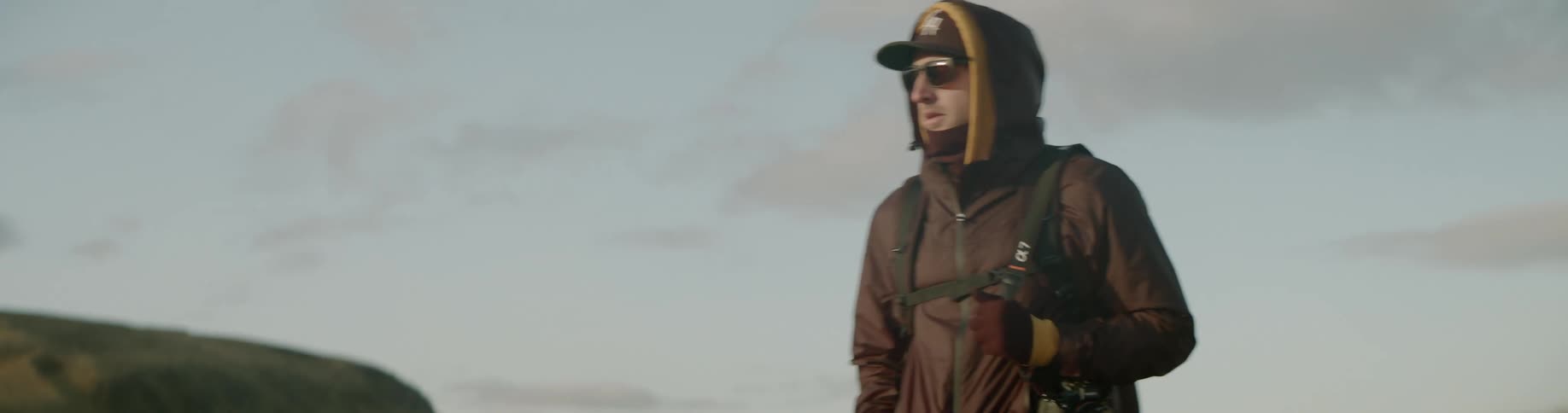 A man carrying his camera walks through a field