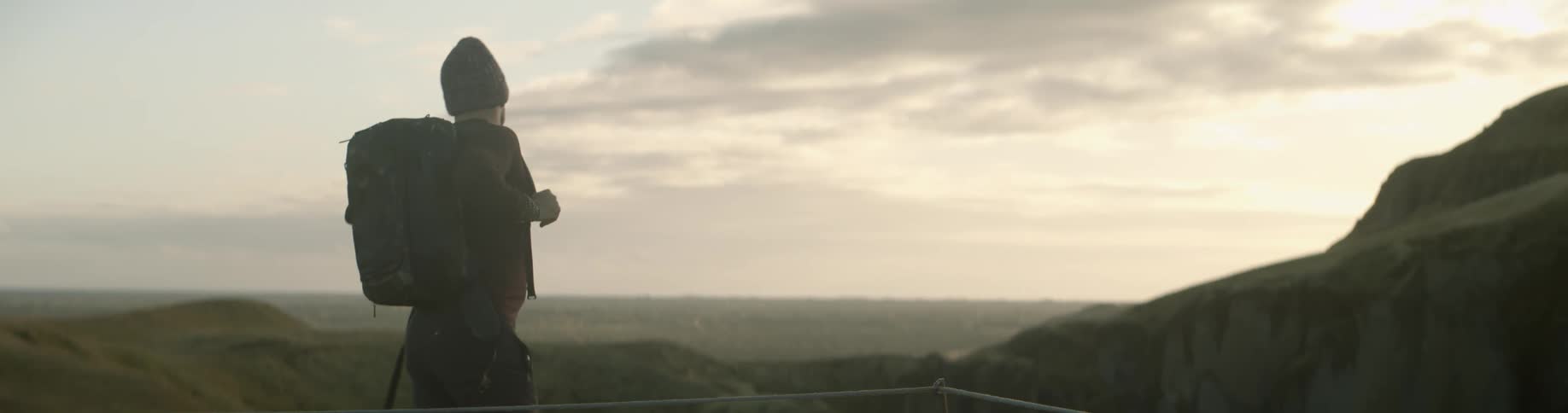 Man wearing backpack prepares to hike at dusk