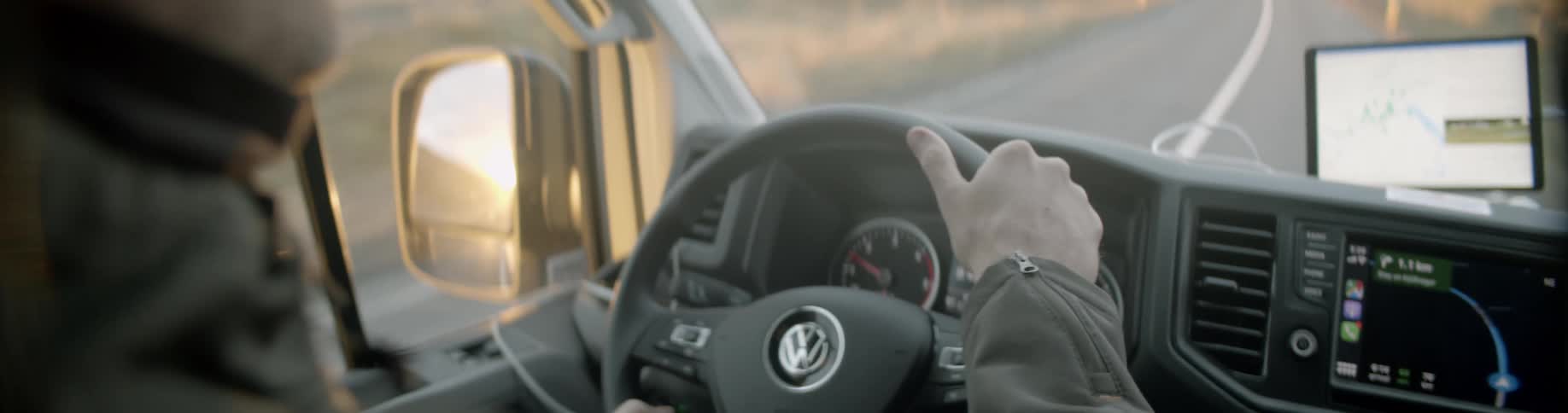 A man drives a volkswagen on a rural road at sunrise