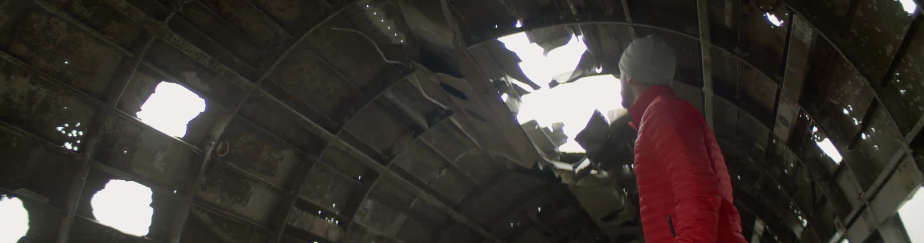 A man walks through the destroyed fuselage of a plane