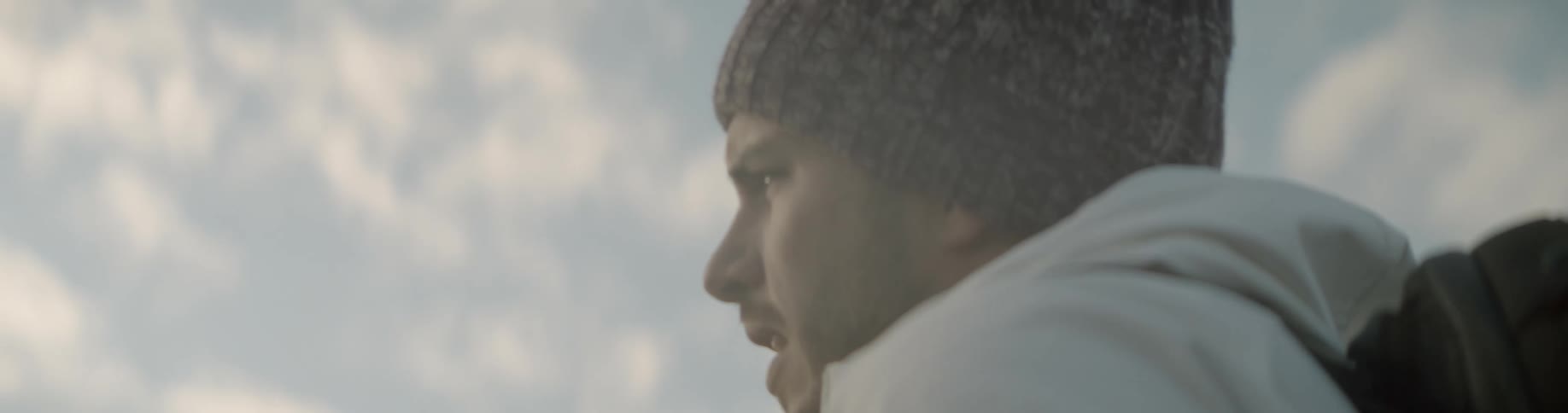 Man wearing a beanie and backpack takes a picture with professional camera outdoors