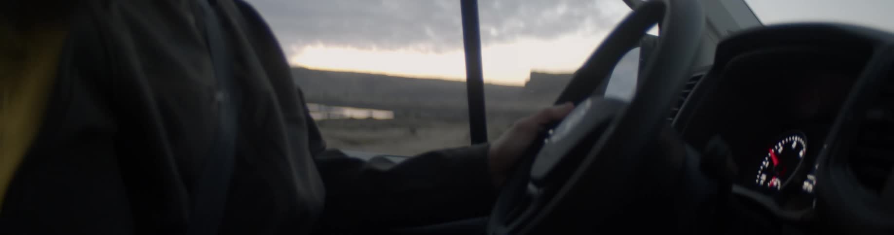 Man wearing a toque talks as he drives his vehicle in a field