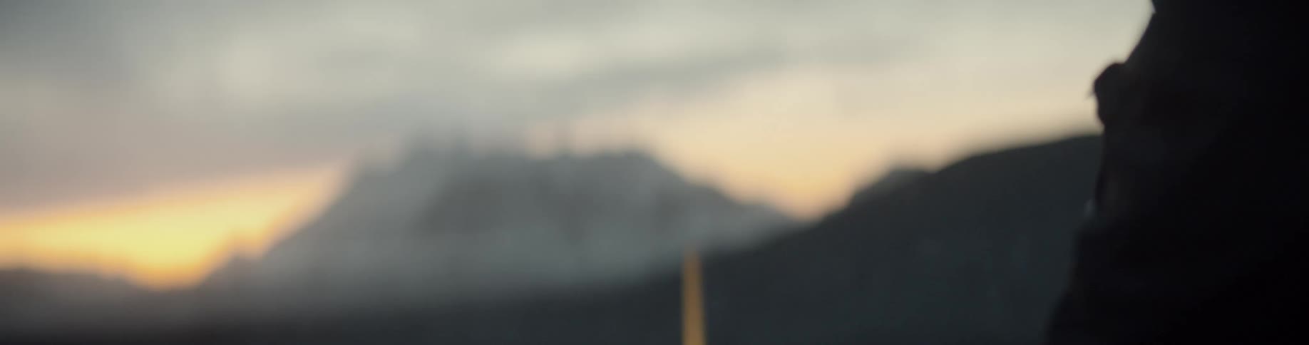A photographer taking photographs of a distant mountain at sunrise