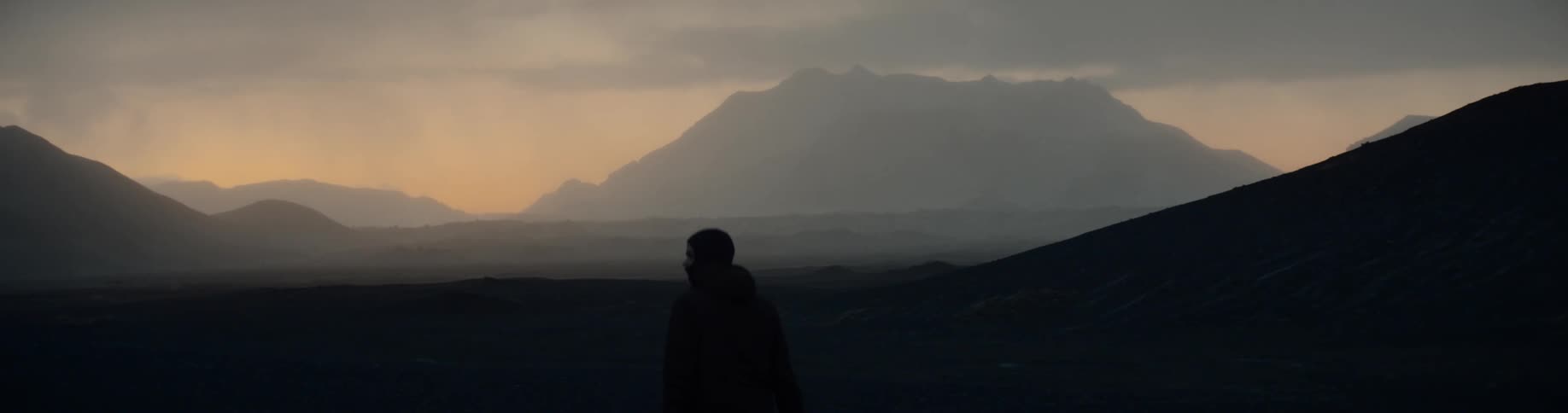 A person walks toward mountains