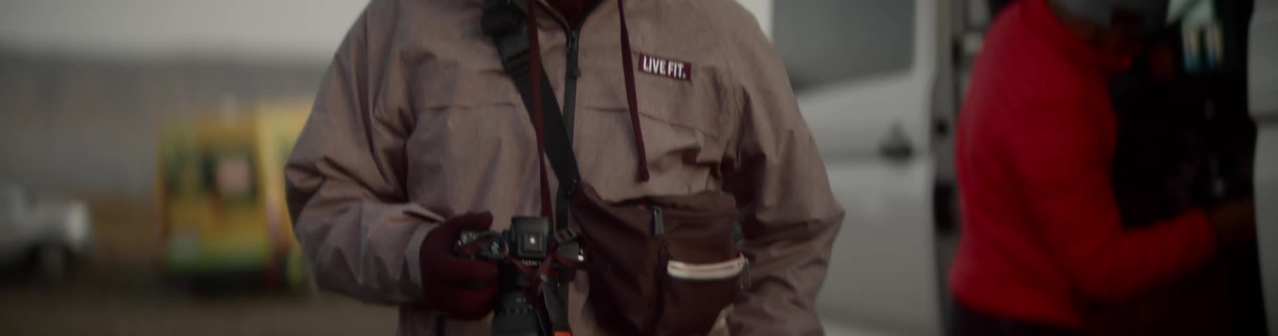 A man takes the lens off his camera and looks through it