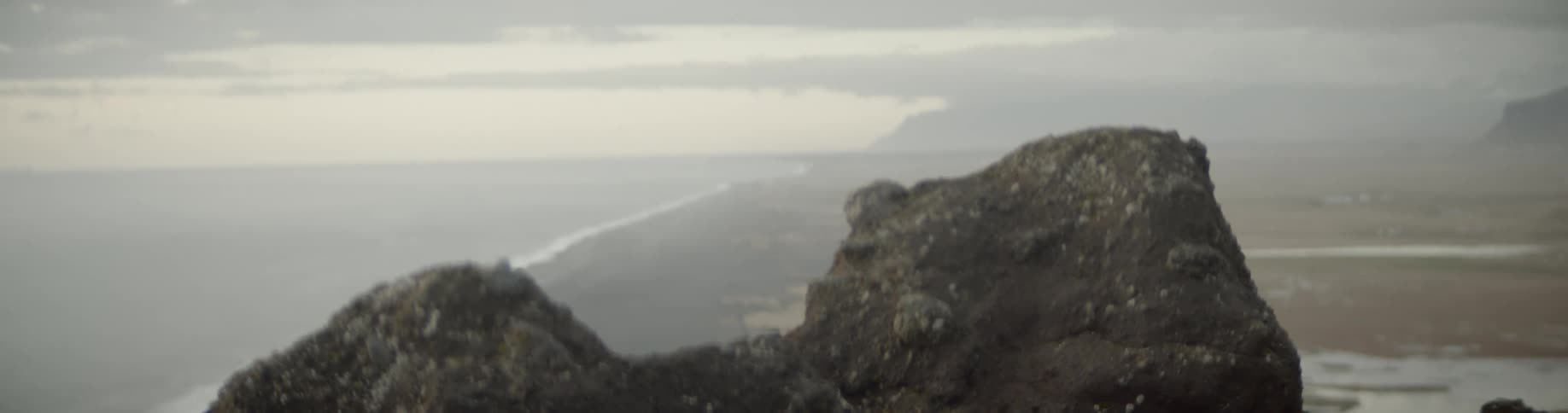 A large cliff in front of waves rolling towards the shoreline