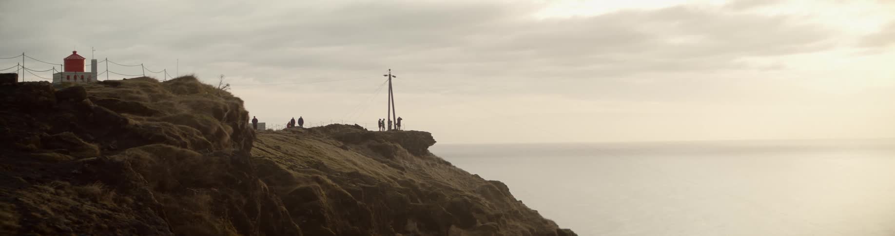 A large cross and building on the edge of a cliff on the coast of the ocean