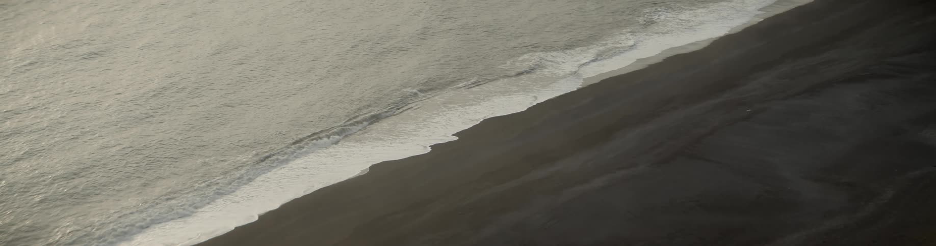 Aerial of shoreline on a black sand beach