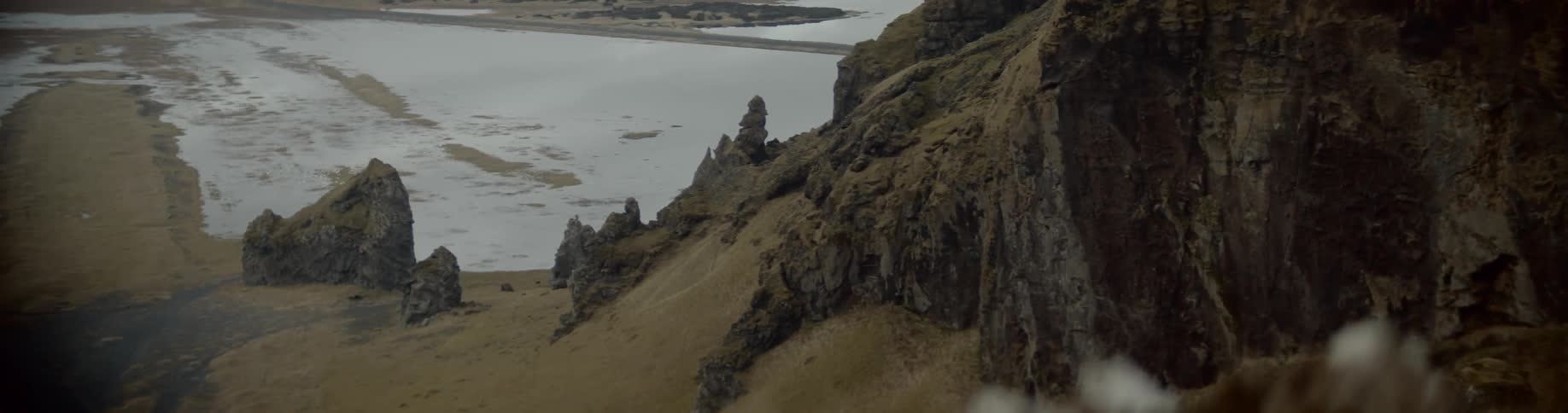 A snow covered field below a cliff
