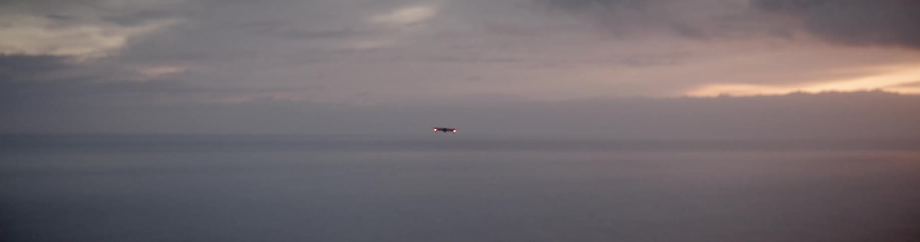 Drone hovering over the sea at sunset