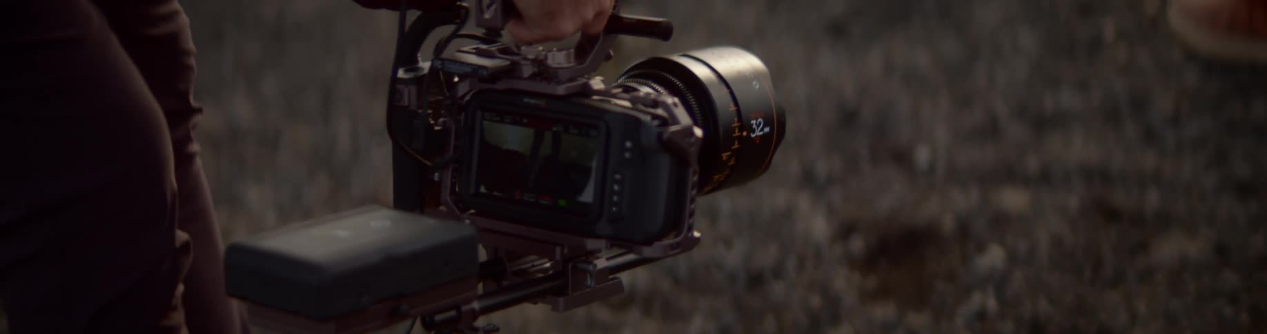 A cameraman holds a camera low shooting a person on a ridge wearing hiking boots