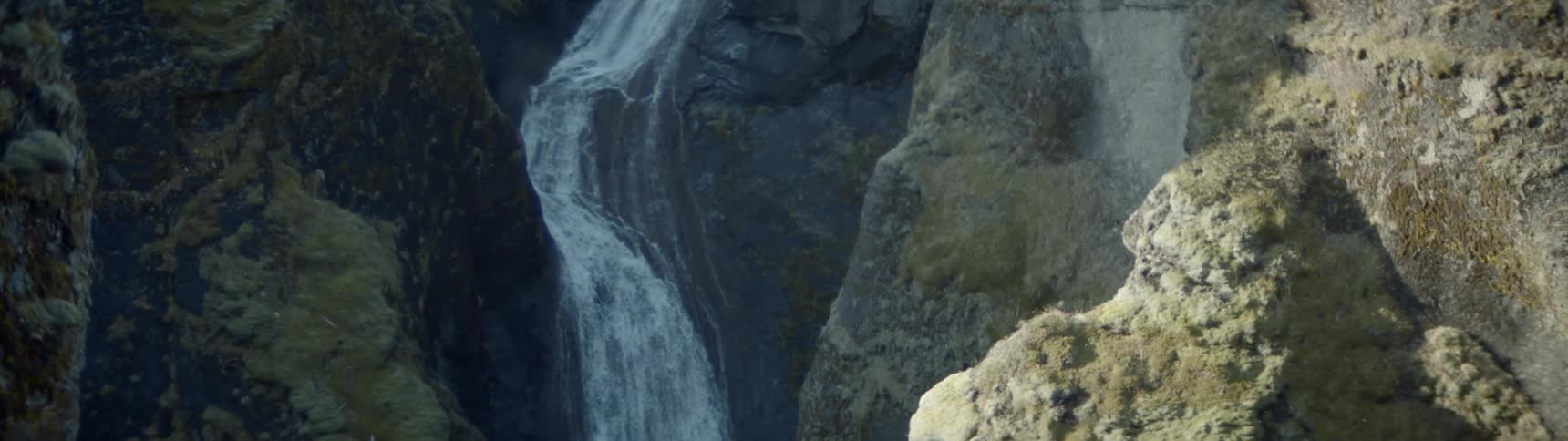 Large waterfall cascades into rocky canyon