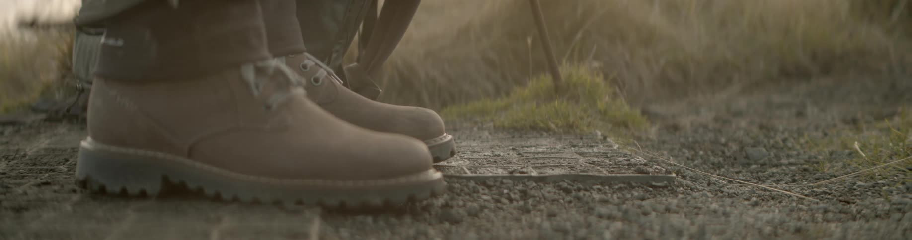 Close up of boots taking a step then a backpack and camera being placed on the ground