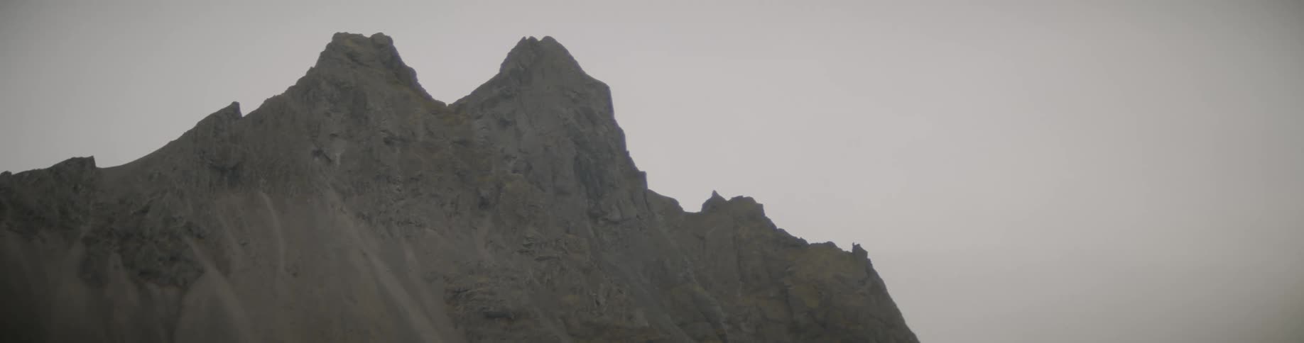 Small peaks sit on top of a cliff under dreary gray skies