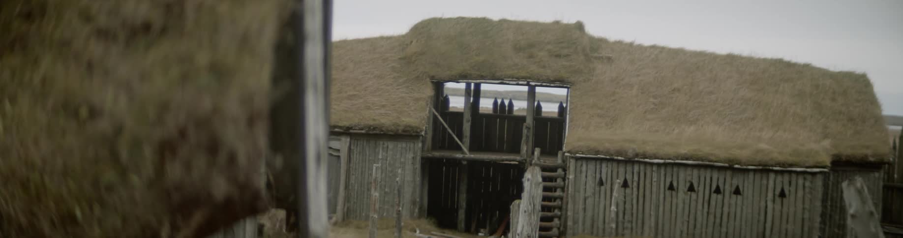 Sod roofed buildings sit under a cloudy sky