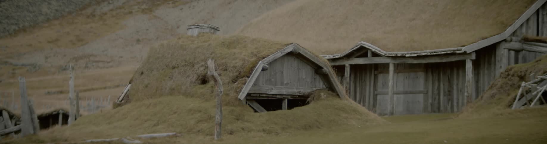 Thatched roofed buildings stand near slope