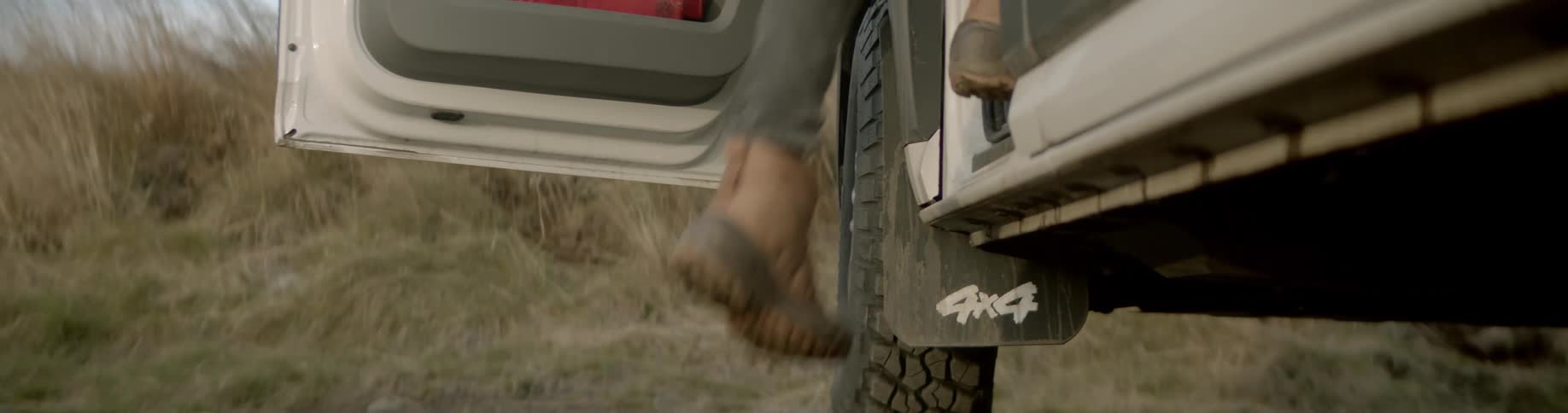 Person steps up into vehicle in field