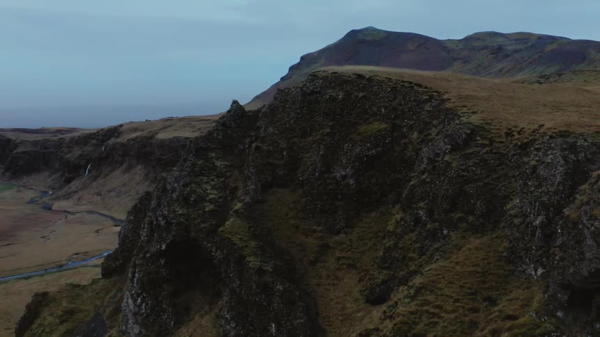 Aerial footage of tall cliffs above a valley with river