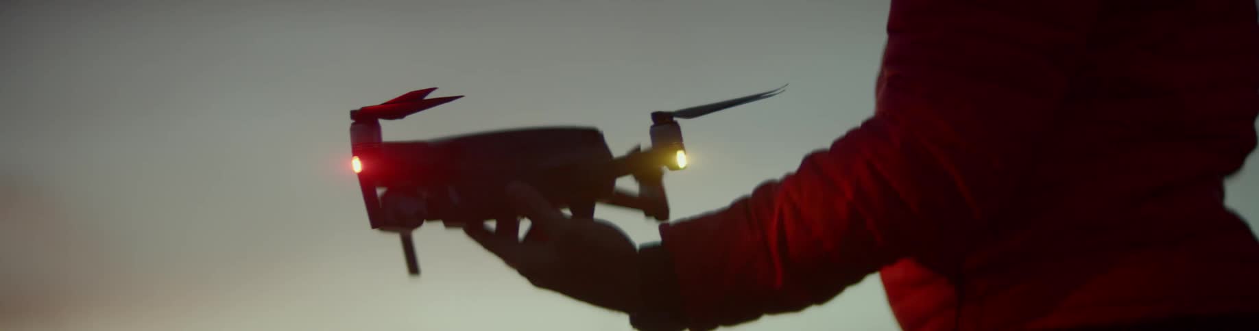A person holds a drone at night