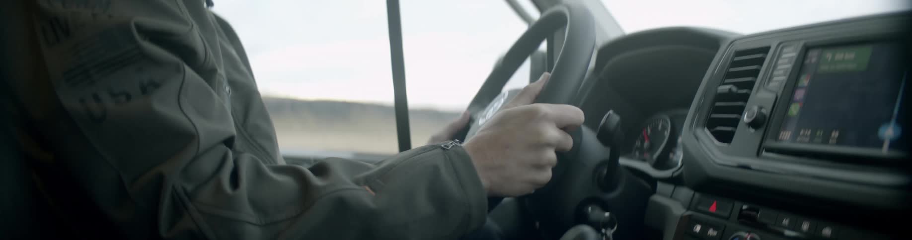 Man wearing a toque and a jacket grips the steering wheel as he drives a vehicle