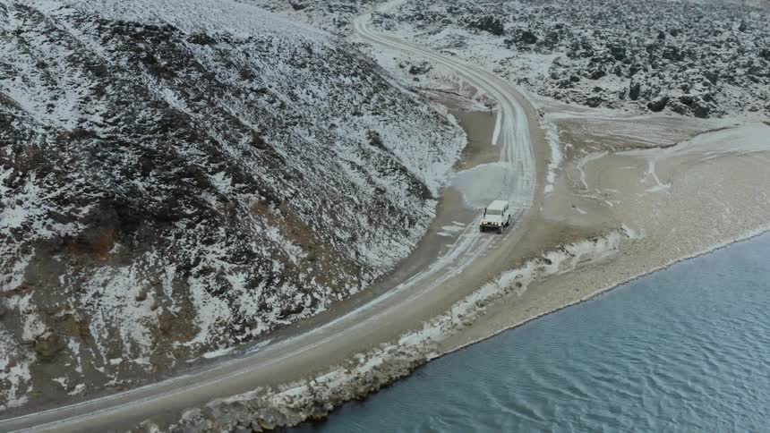 Birds eye view of a vehicle stopped on the road beside the water