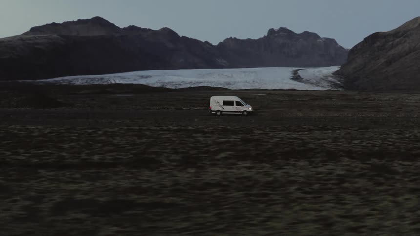 A vehicle drives along barren land