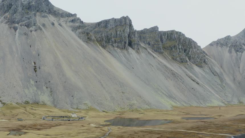 Steep slopes lead down from jagged cliffs and mountains and into the grassy valley below