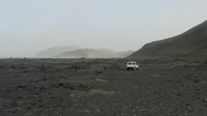 An suv vehicle drives on an off road terrain by a mountain