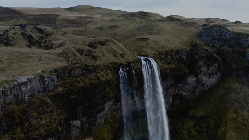 A cliff with a waterfall with the sky in the background