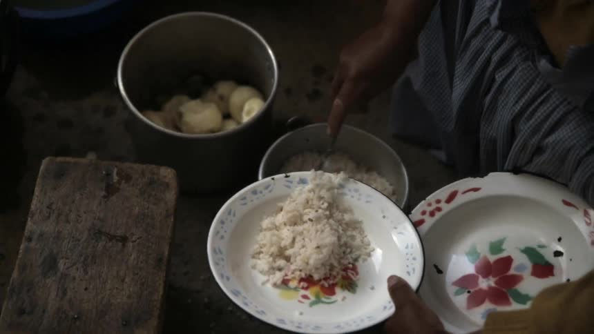 A person scoops rice from a pan onto a plate