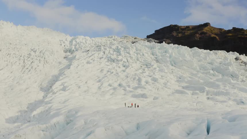 People stand at the bottom of a snow covered mountain