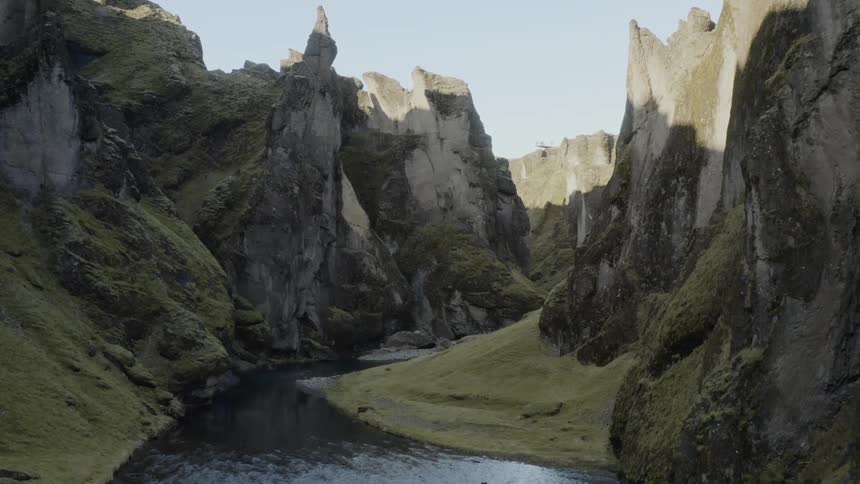 Drone footage of river in deep canyon surrounded by high jagged cliffs