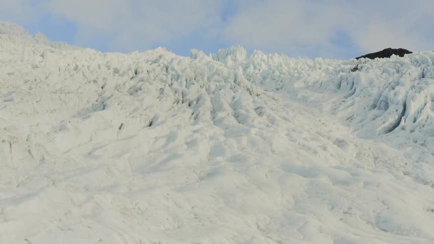 Glacier lays near mountain under cloudy sky