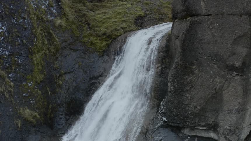 Aerial of hidden waterfall rushing down through the canyon