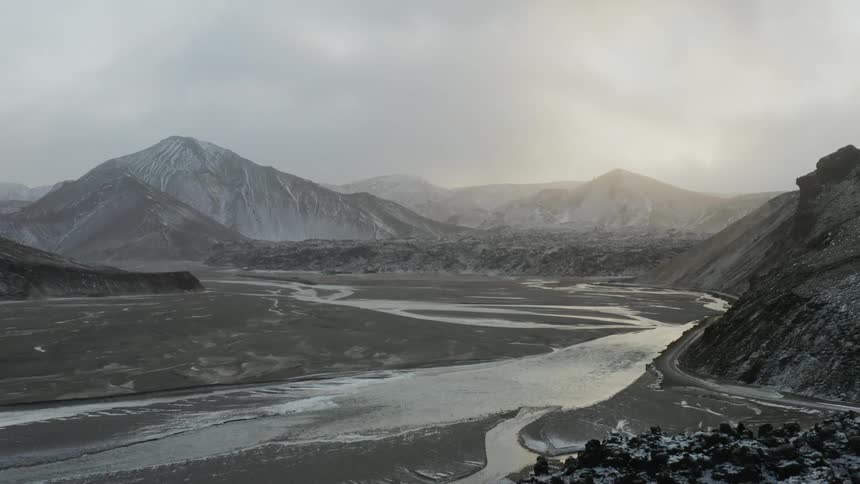 River runs through rocky mountains with light snow cover
