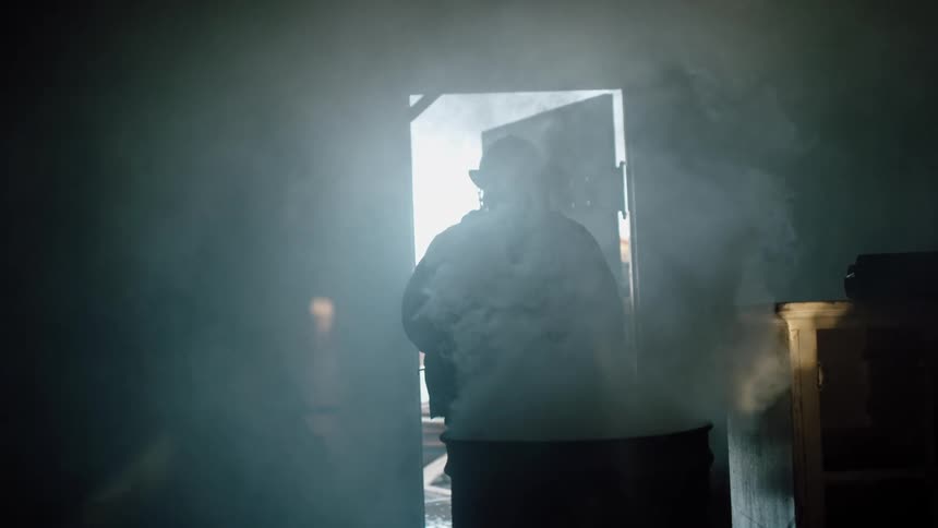 Fireman standing in front of smoking barrel then walking outdoors