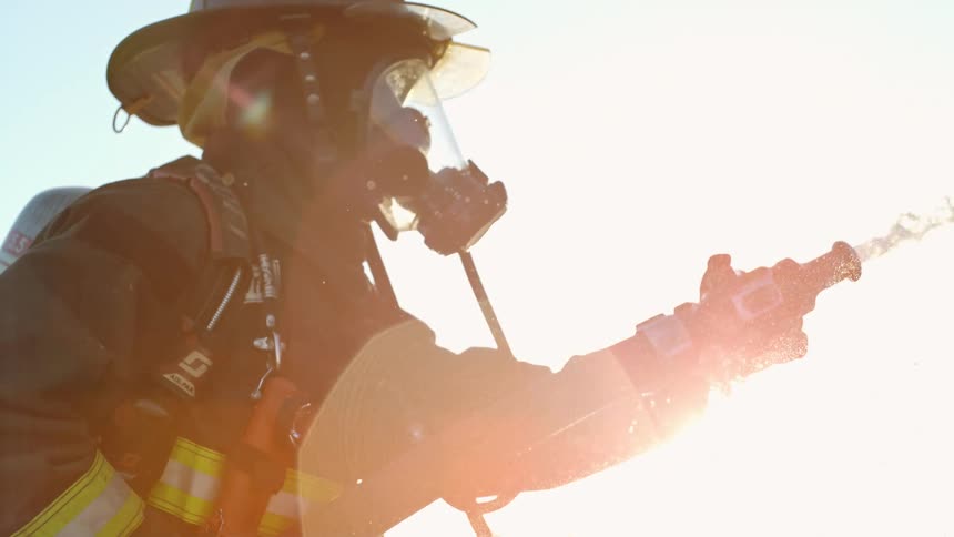 A firefighter holds a hose and sprays water