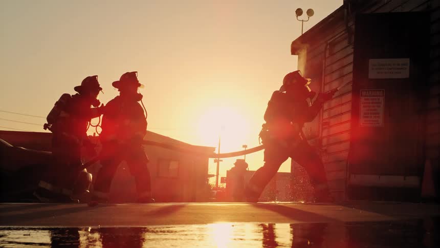 Three firefighters stand outside of a building