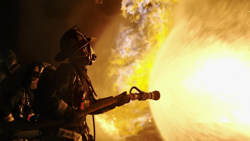 Firefighters holding a fire hose putting out a fire
