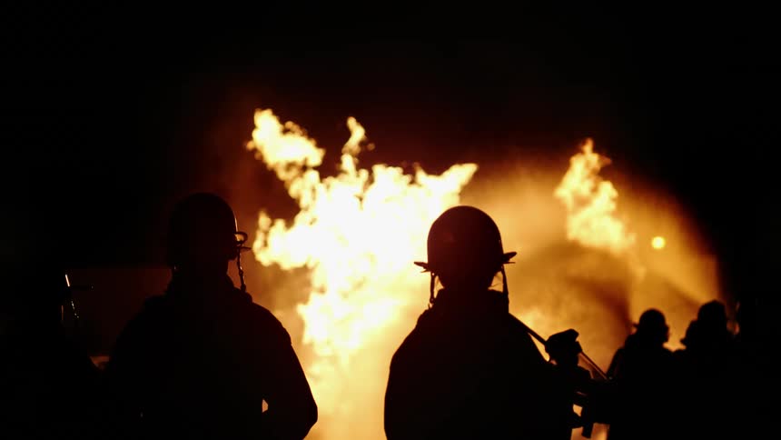Silhouettes of firefighters putting out a fire
