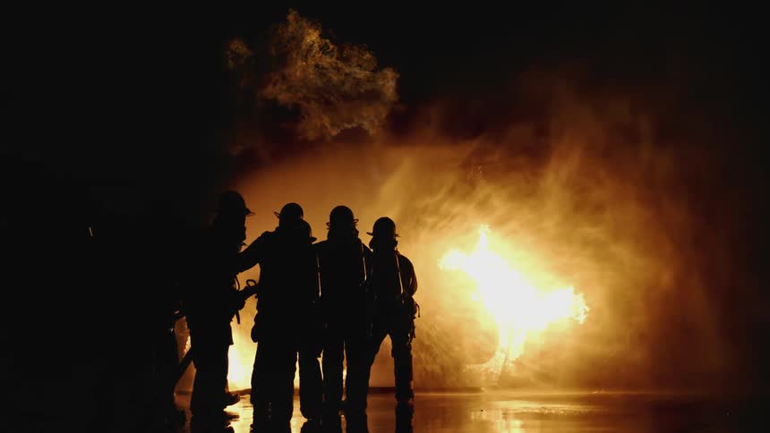 A group of firefighters put out a fire at night