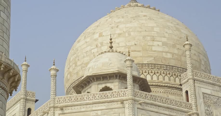 Birds fly away from the dome and turrets of the taj mahal on a sunny day