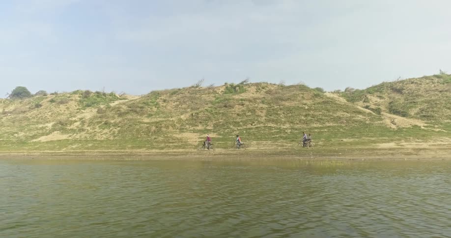 Bike riders riding along side the lake on a trail near hills in India