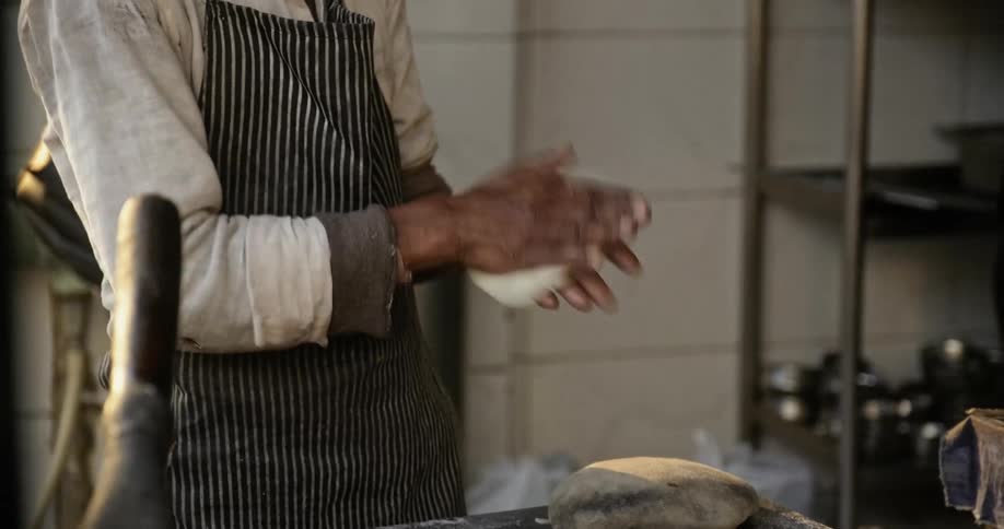 Man tosses dough back and forth in his hands making street food